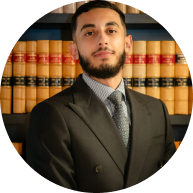 Professional portrait of a female Krayemandco criminal lawyer in a navy blazer standing in front of a law library.