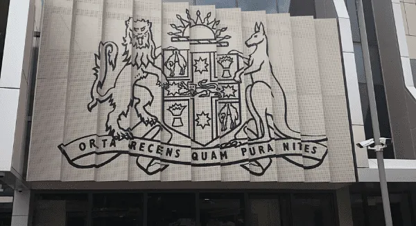 The New South Wales Coat of Arms featuring a lion and kangaroo above the motto Orta Recens Quam Pura Nites at a courthouse entrance for a Criminal defence firm Sydney CBD.