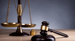 A conceptual image featuring a vintage brass scale of justice and a dark wooden judge's gavel with a gold band resting on a wooden desk, used by a leading Criminal defence lawyer Sydney firm.